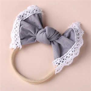 Detail of grey bow baby headband with white lace edging and nude seamless elastic band