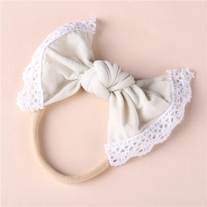 Close-up of soft nylon baby headband with cream cotton bow and white lace trim detail
