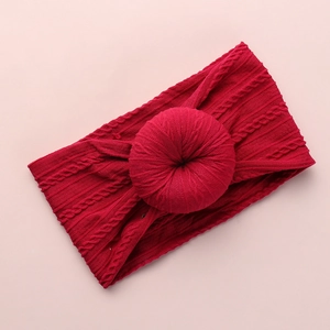 Close-up of red cable-knit baby headband with a decorative donut shaped knot detail