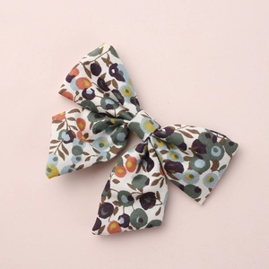 Macro detail of kids floral bow hair clip showing blue and orange fabric texture