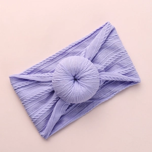 Detailed knit texture of light purple baby headband with donut knot on pink backdrop