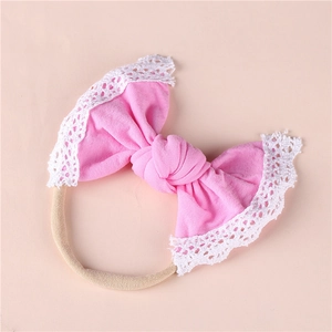 Close-up of baby headband with pink knit bow, white lace trim and nude nylon band