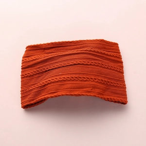 Detail of caramel knitted baby headband featuring intricate cable stitch and ribbed patterns