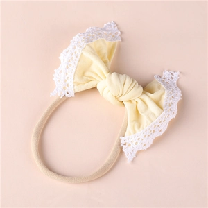 Close-up of baby nylon headband featuring a yellow bow with delicate white lace trim