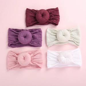 Close-up of five knitted baby headbands with donut-shaped knots in various soft colors