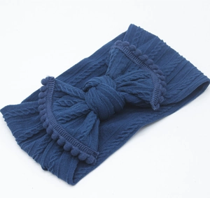Vue détaillée du bandeau bébé bleu marine en maille torsadée avec grand nœud pompon