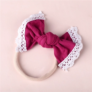 Detail of baby bow headband featuring magenta fabric and delicate white lace edges