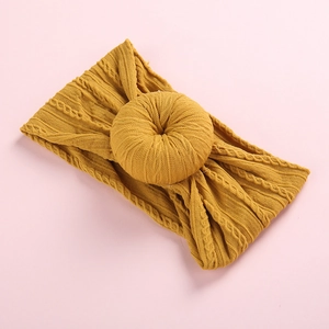 Ginger yellow baby headband with knit texture and large donut knot on pink background