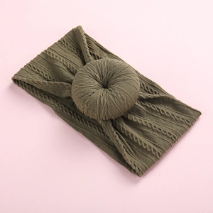 Detail of army green cable knit baby headband with 3D doughnut bow on pink backdrop