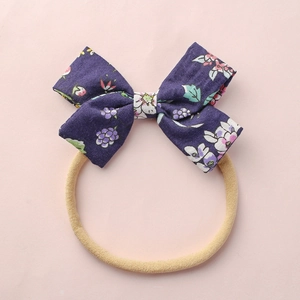 Deep purple floral bow baby headband with elastic nylon band on pink background