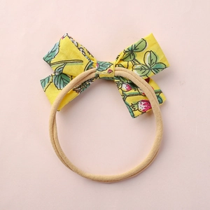 Detail of floral baby headband with pink strawberry pattern on yellow nylon elastic loop