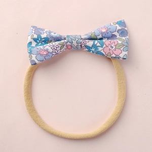 Vue détaillée d'un bandeau pour bébé avec nœud en coton floral et élastique doux en nylon