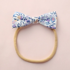 Détail du nœud floral en coton sur un bandeau bébé élastique en nylon de couleur chair