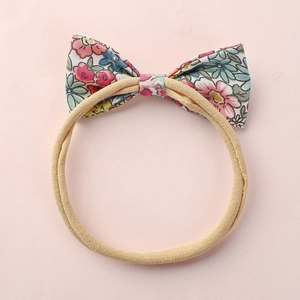 Vue détaillée du bandeau bébé à nœud floral avec élastique en nylon de couleur chair