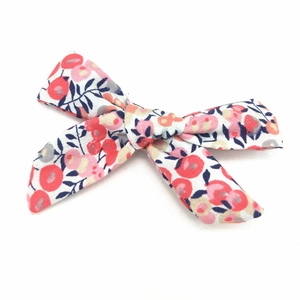 Fermaglio per capelli con fiocco in cotone a fiori rossi e rosa su sfondo bianco puro