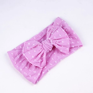 Detail view of pink baby nylon headband featuring a large bow and white polka dots