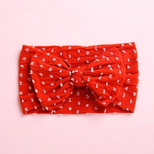 Close-up of bright red nylon baby headband featuring a large bow and white polka dots