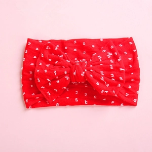 Detailed close-up of bright red infant headband with white polka dots and large soft bow