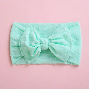 Detail of mint green nylon baby headband featuring soft pompom texture and bow knot