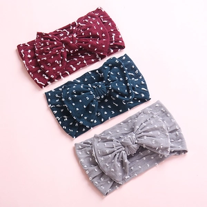 Detailed view of soft nylon baby headbands with large bows in red, navy, and grey tones