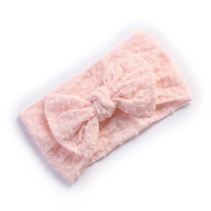 Close-up of soft pink baby headband with Swiss Dot texture and large bow on white back
