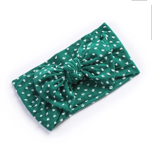 Detail of green bow headband with white polka dots and soft nylon knit texture