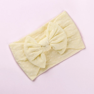 Dettaglio della fascia per neonati in nylon giallo chiaro con grande fiocco a pois bianchi