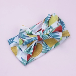 Détail de l'imprimé fruits tropicaux et nœud en tricot sur bandeau bébé élastique