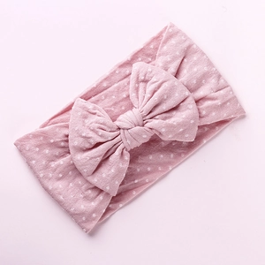 Dettaglio della fascia per neonati in nylon rosa a pois bianchi con grande fiocco decorativo