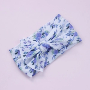 Détail d'un bandeau pour bébé avec imprimé floral doux et grand nœud décoratif