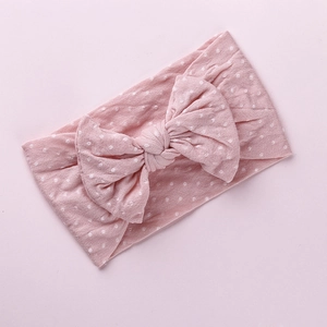 Dettaglio della fascia in nylon rosa a pois con un grande fiocco per neonata