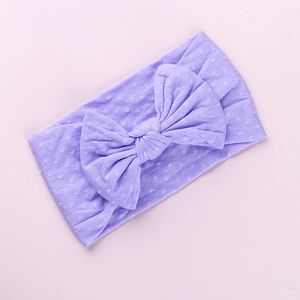 Dettaglio fascia elastica in nylon viola a pois con grande fiocco per neonati