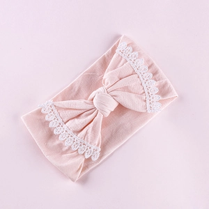Pink elastic baby headband with large lace-edged bow in soft breathable cotton