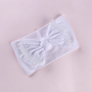 White nylon baby headband with large lace embroidered bow on a soft lavender background