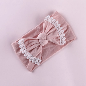 Detail of pink baby headband featuring soft knit fabric and white floral lace bow