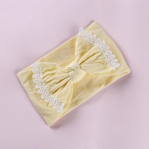 Close-up of soft yellow baby headband featuring lace edges and a large bow detail