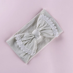 Detail of baby headband with grey knit fabric and white lace-edged bow decoration