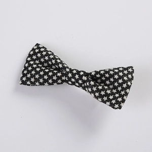 Close-up of fabric bow hair clip featuring black and white star pattern on woven texture