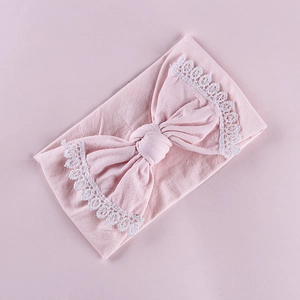 Close-up of pink baby headband showing delicate white lace edges on a large bow