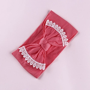 Detail of coral pink baby nylon headband with white lace trim and bow knot design