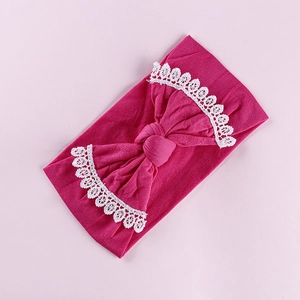 Close-up of bright rose pink baby headband with large lace-edged bow and knit texture