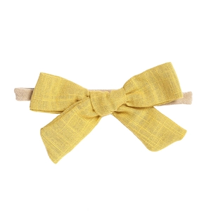 Detail of ginger yellow bow headband featuring soft fabric texture and elastic nylon band