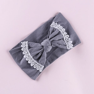 Detailed view of gray knit baby headband featuring an oversized bow with white lace trim