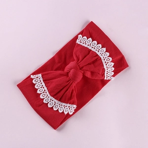 Detailed view of red baby headband with a large bow and white lace embroidery trim