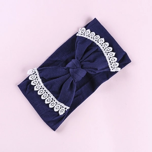 Detailed view of navy blue baby headband featuring white lace embroidery and big bow
