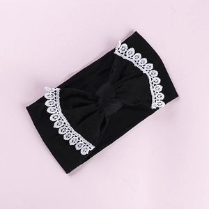 Detailed close-up of baby nylon headband with large black bow and white lace trim edge