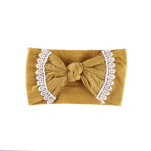Mustard yellow baby headband with large lace embroidery bow on soft nylon fabric
