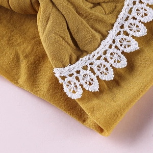 Close-up of ginger yellow baby headband with delicate white floral lace embroidery details