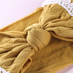 Detailed macro view of mustard yellow knit baby headband with white lace edges