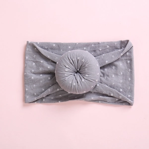 Detailed close-up of a grey elastic baby headband with white polka dots and donut knot
